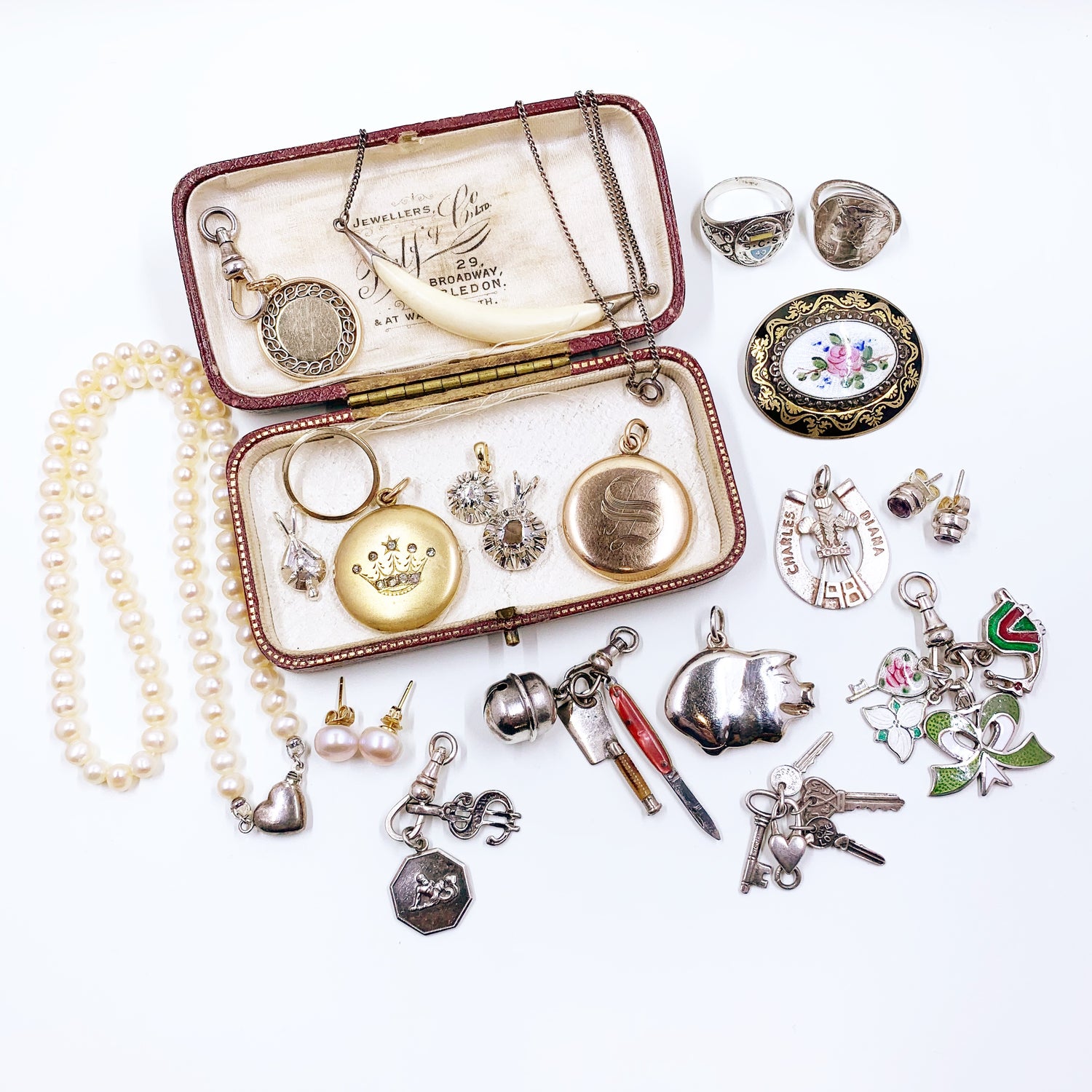A variety of antique and vintage jewelry spread out around an antique jewelry presentation box
